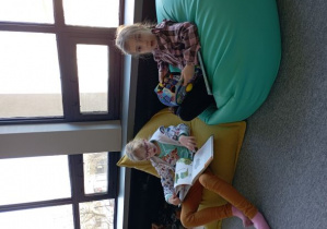 Dziewczynki na kolorowych siedziskach oglądają książki